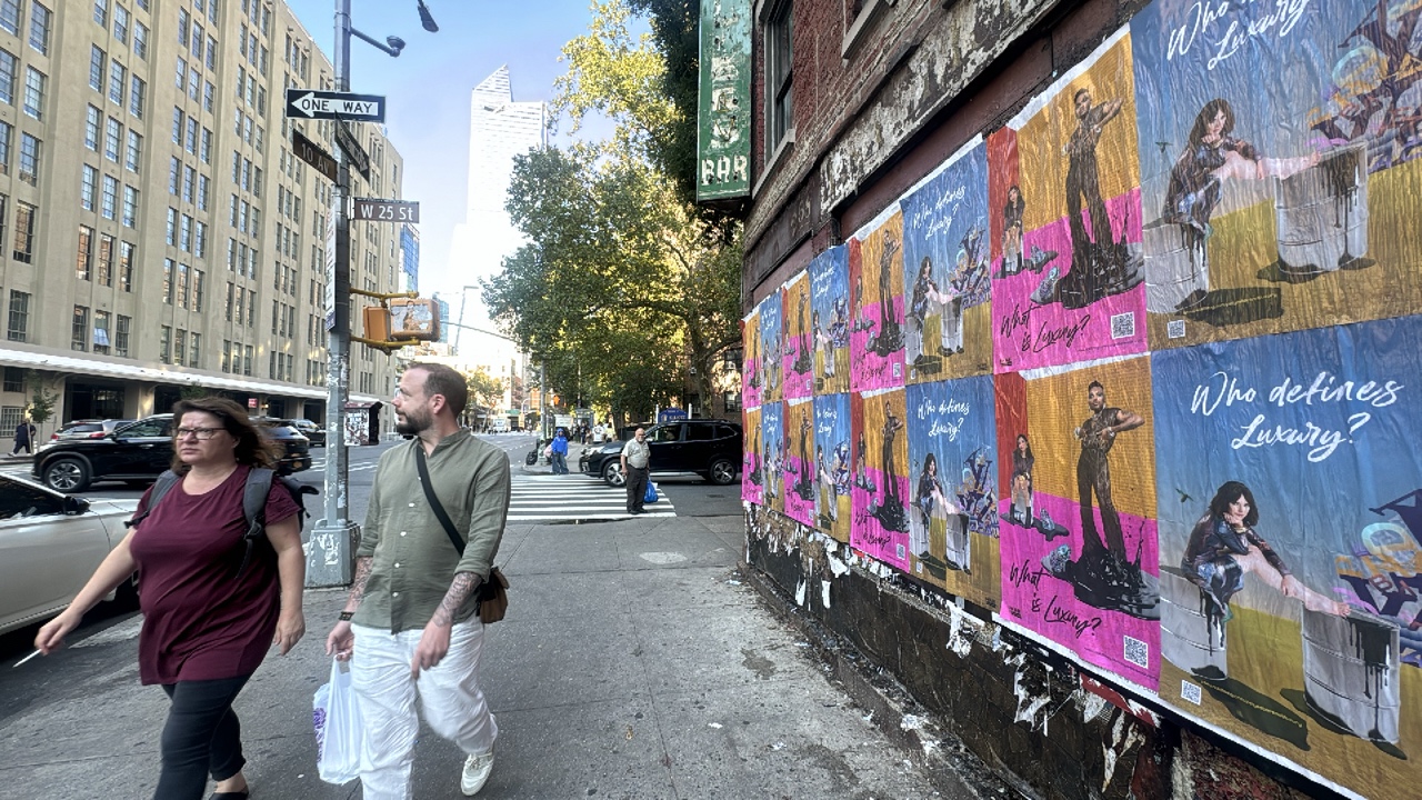 A long row of Is This a Luxury Item campaign posters wheat-pasted along West 25th Street in New York