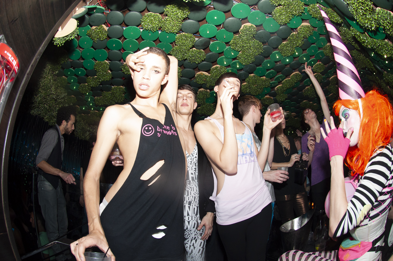 A crowded downtown club beneath a green patterned ceiling