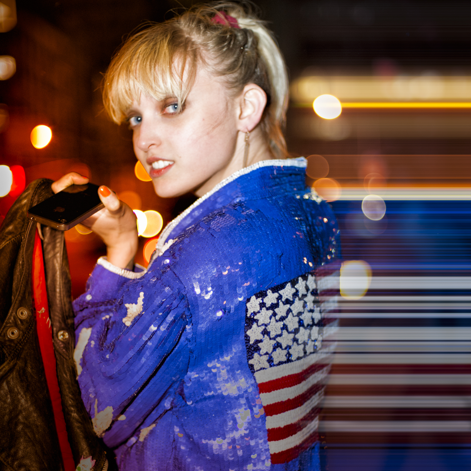 A clubgoer in a blue sequined jacket surrounded by streaks of city light