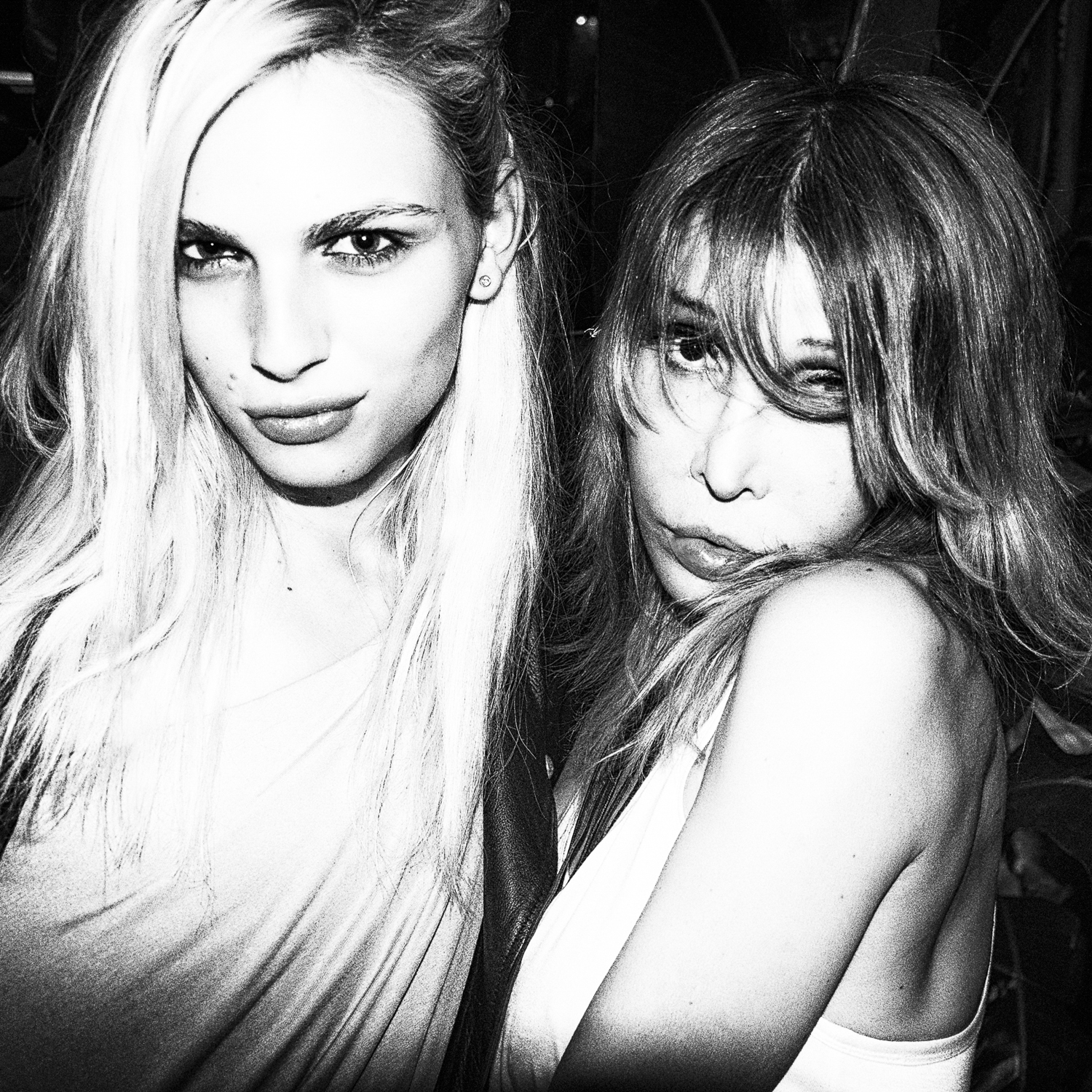 A high-contrast black-and-white close-up of two nightlife figures