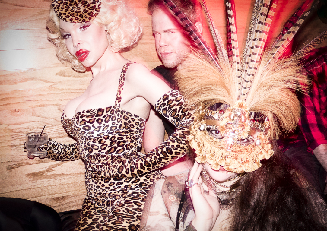 Three elaborately dressed nightlife figures wearing leopard print, feathers and masks